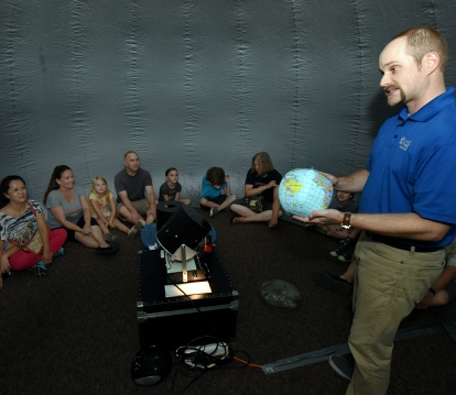 Male instructor showing a globe to workshop attendees inside the StarLab.