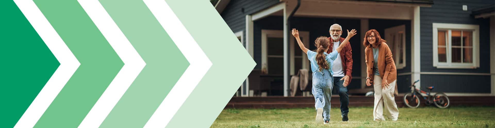 Older couple standing in front of their home waiting for a young girl running toward them with her arms in the air.