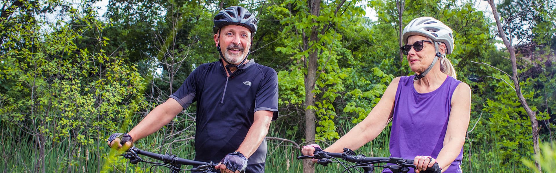 Older adults enjoying a summer day riding bikes in the park.