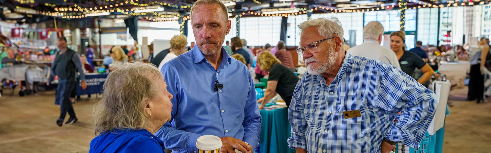 County Executive David Coulter and Jim Ellison talk with a senior resident at the 2023 Senior Expo in Royal Oak, Michigan.