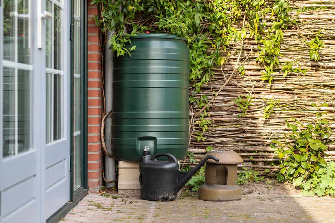 A rain barrel next to the patio door and against the home