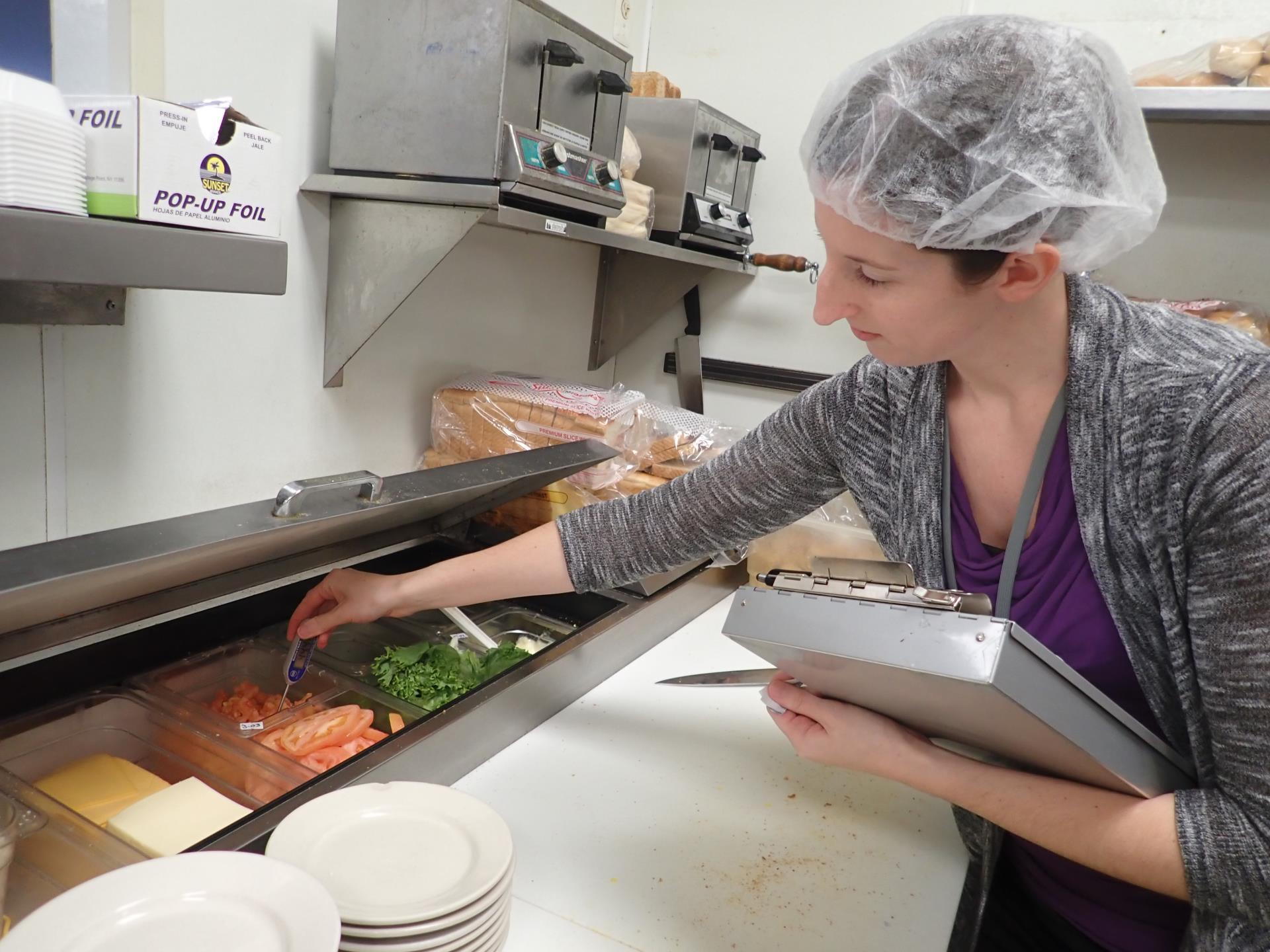 Public Health Sanitarian conducting a food inspection in a restaurant kitchen.