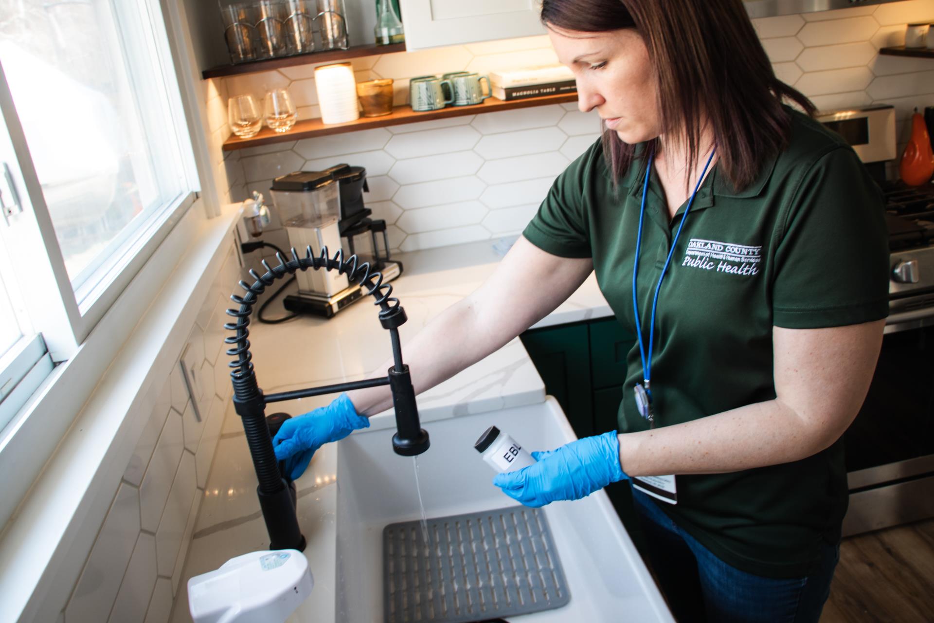 Public Health Sanitarian testing water in a kitchen.