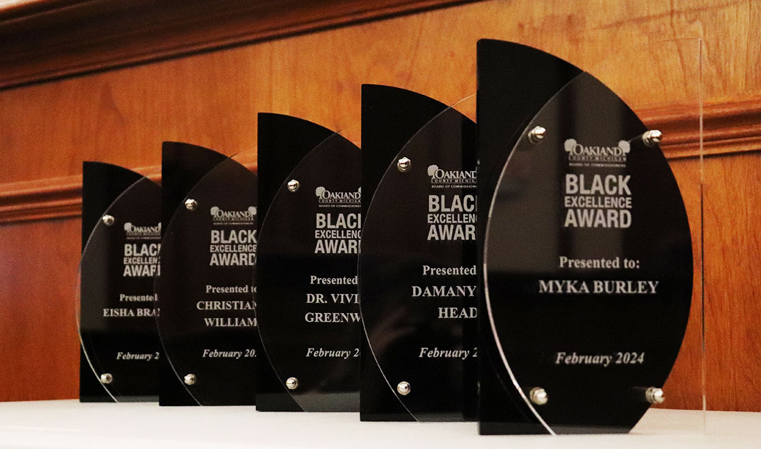 Five black and acrylic awards lined up on a table for display