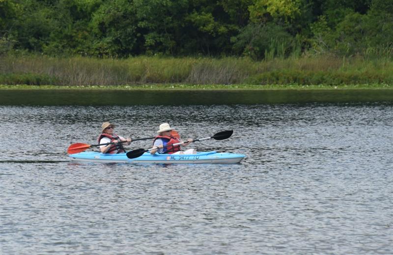 Two older adult women kayaking at the lake.