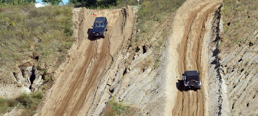 Aerial view of two trucks driving opposite directions along a dirt off-roading course