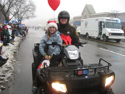 Reserve Deputy with a child riding an ATV in Christmas parade