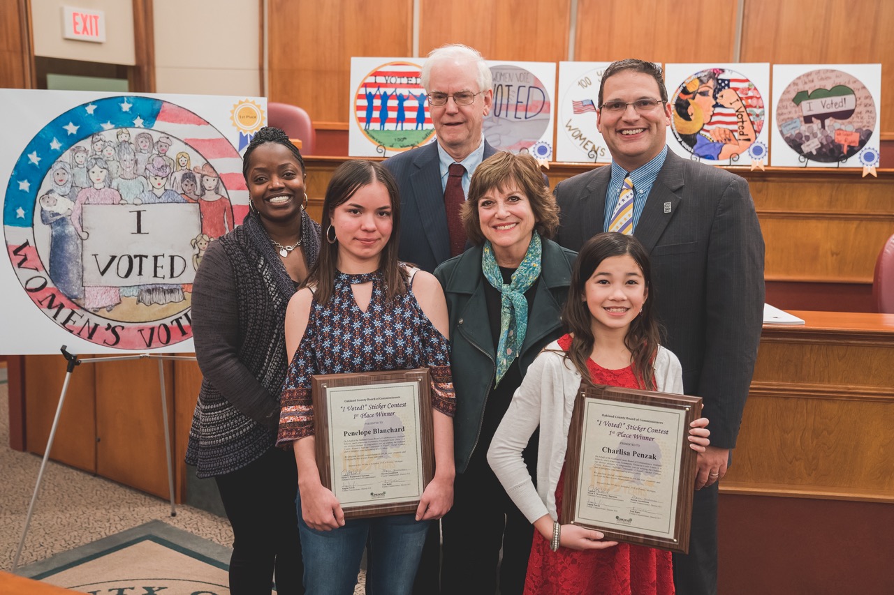 1st place contest winners Penelope Blanchard (left) and Charlisa Penzak (right) with members of the Board’s Women’s Suffrage Committee, which include (left to right) Angela Powell, Tom Kuhn, Marcia Gershenson and Dave Woodward.