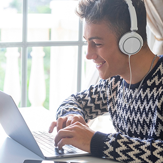 Person with headphones typing on laptop