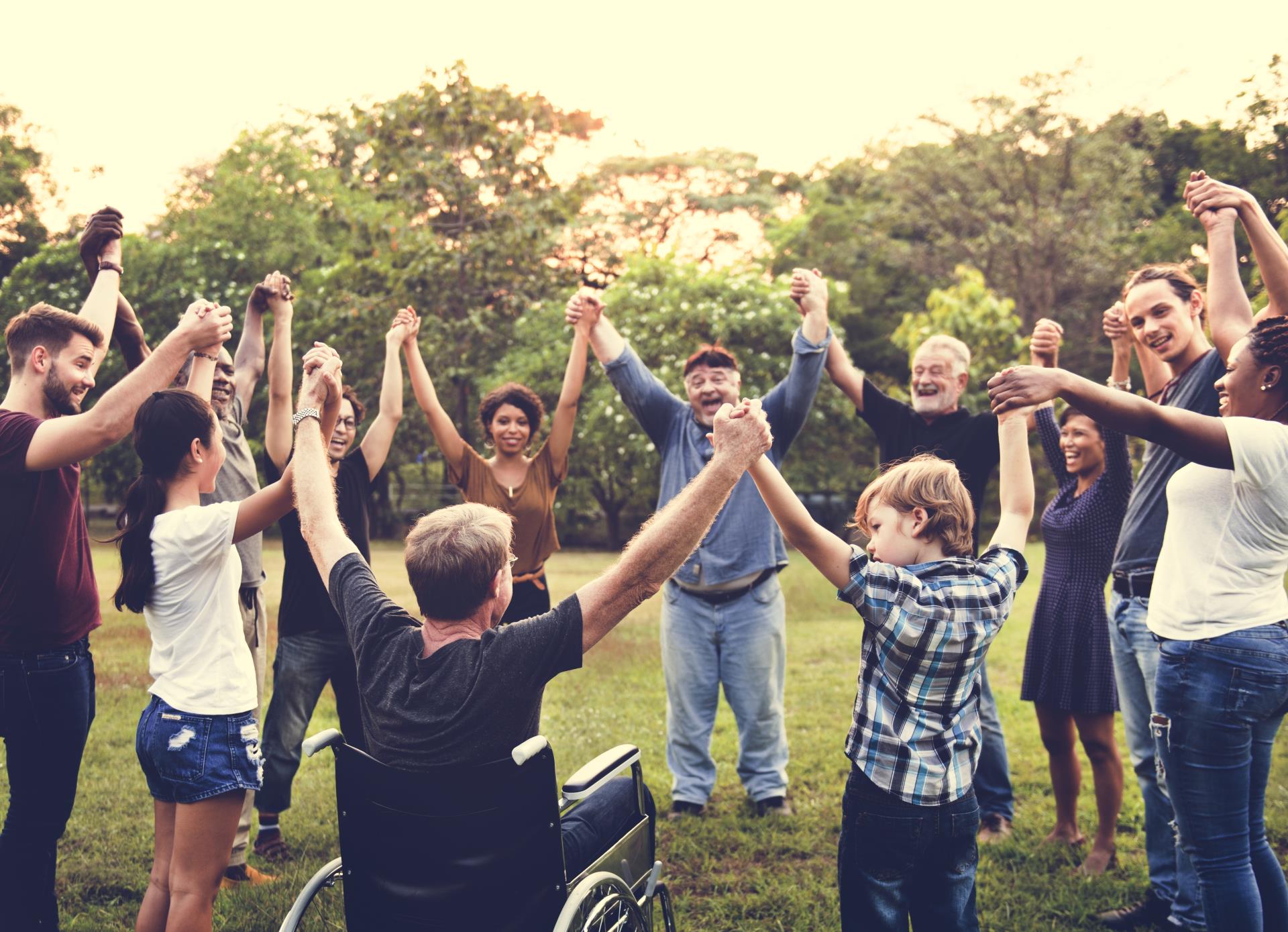 People of varying ages, ethnicities, and abilities standing in a circle holding hands