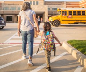 Adult and child walk into school building.